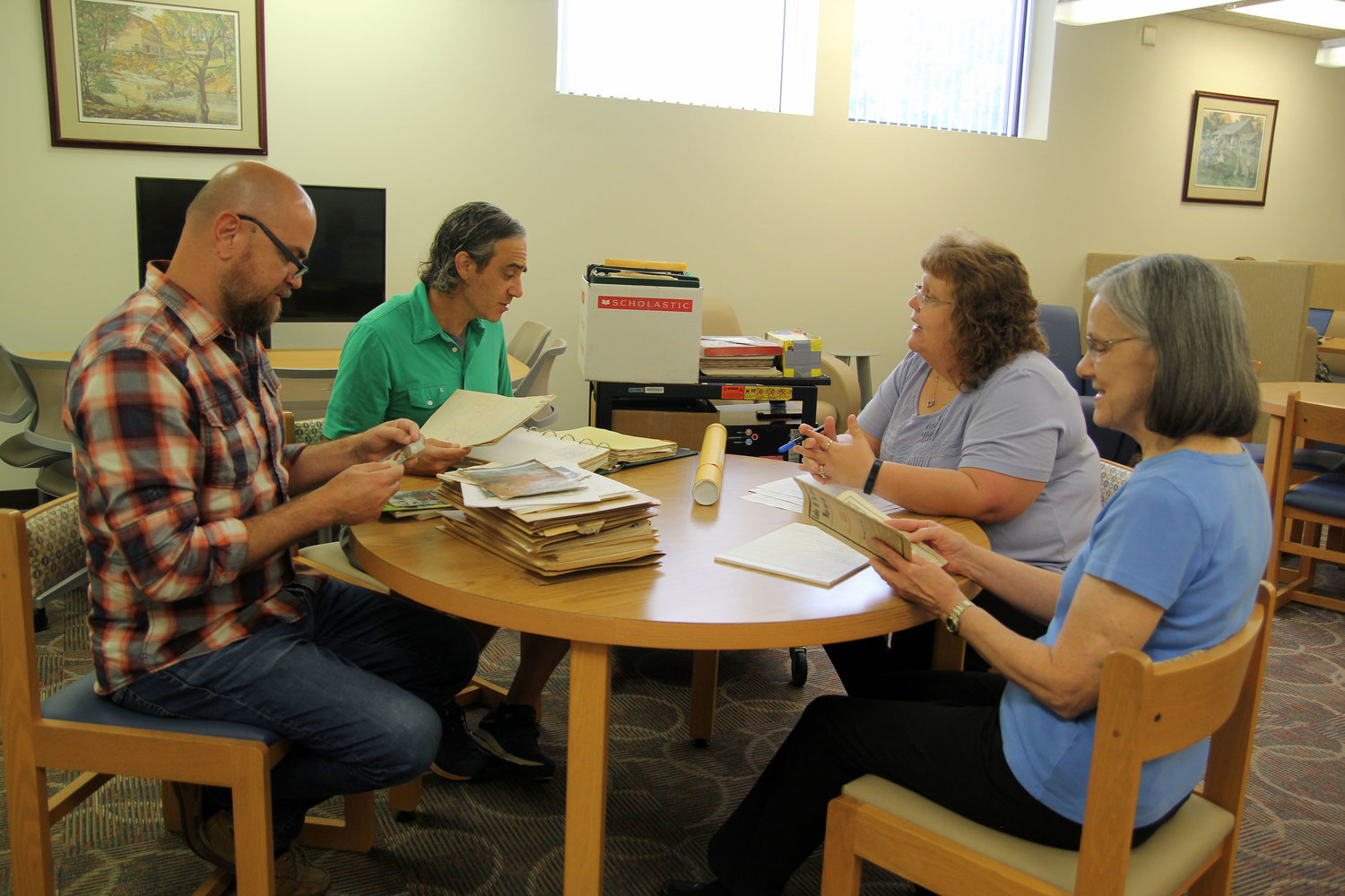 THESE MEMBERS OF THE OZARKS Heritage Resource Center advisory committee at Missouri State University-West Plains (MSU-WP) look through some of the historical materials that could be housed in the center when it opens in 2022 in the Garnett Library. From left are Professor of English Frank Priest, Associate Professor of History Dr. Jason McCollom, Garnett Library Director of Library Services Rebekah McKinney and Assistant Librarian Neva Parrott.